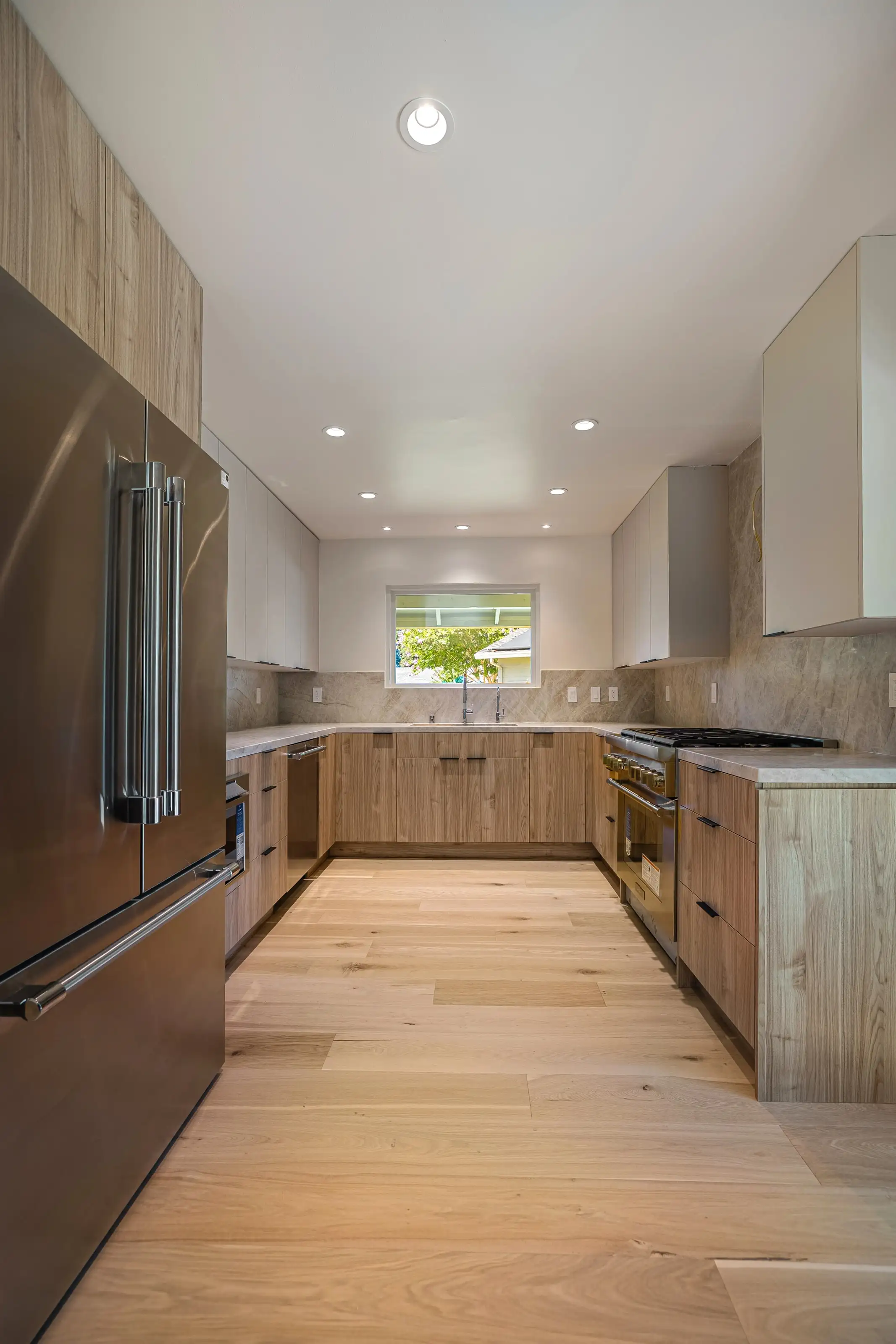 Contemporary kitchen remodel in San Jose with natural wood cabinets, stainless steel refrigerator, and modern lighting.