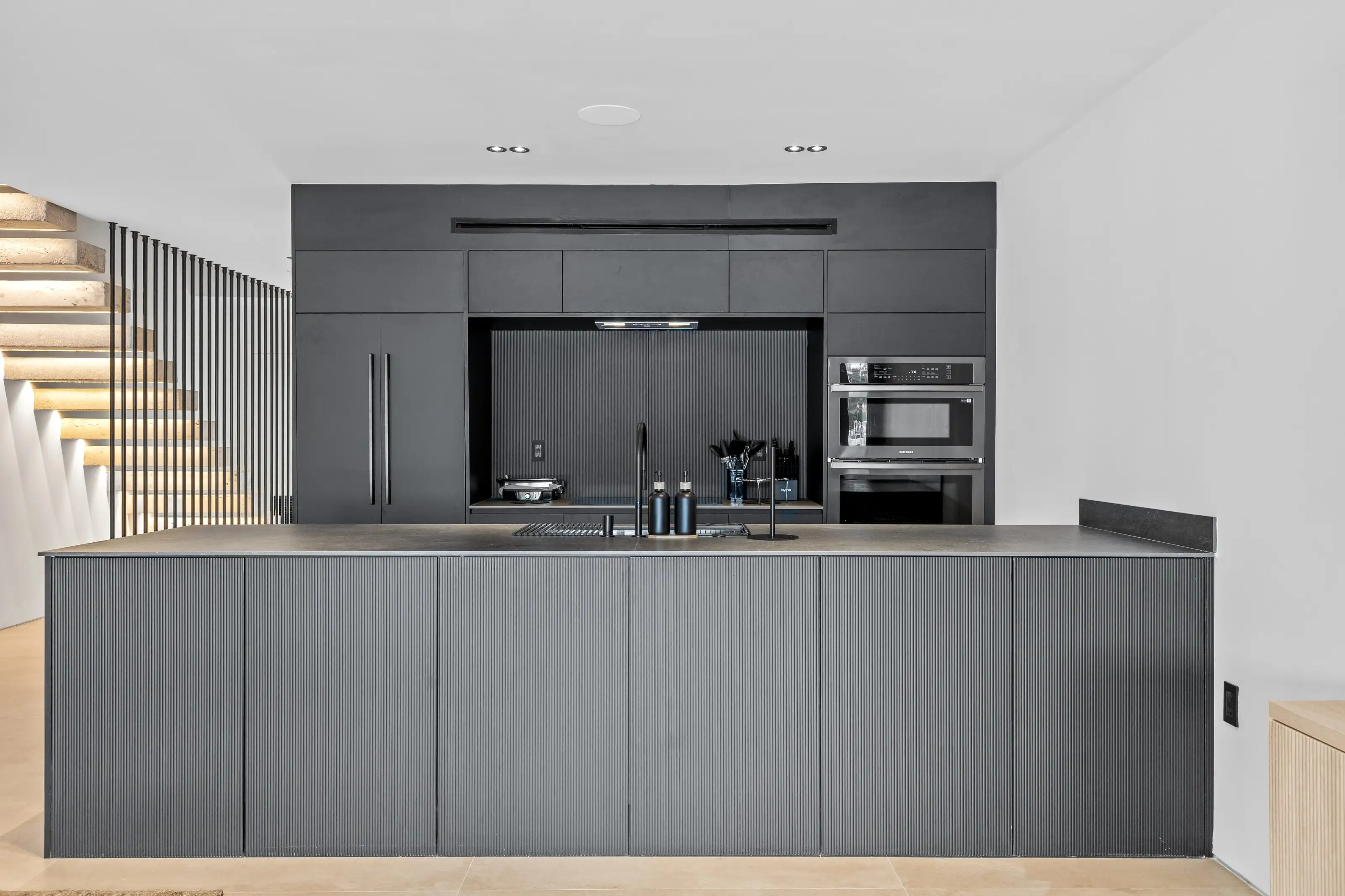 Open-concept living room and modern black kitchen remodel in San Jose with custom cabinetry and neutral tones.
