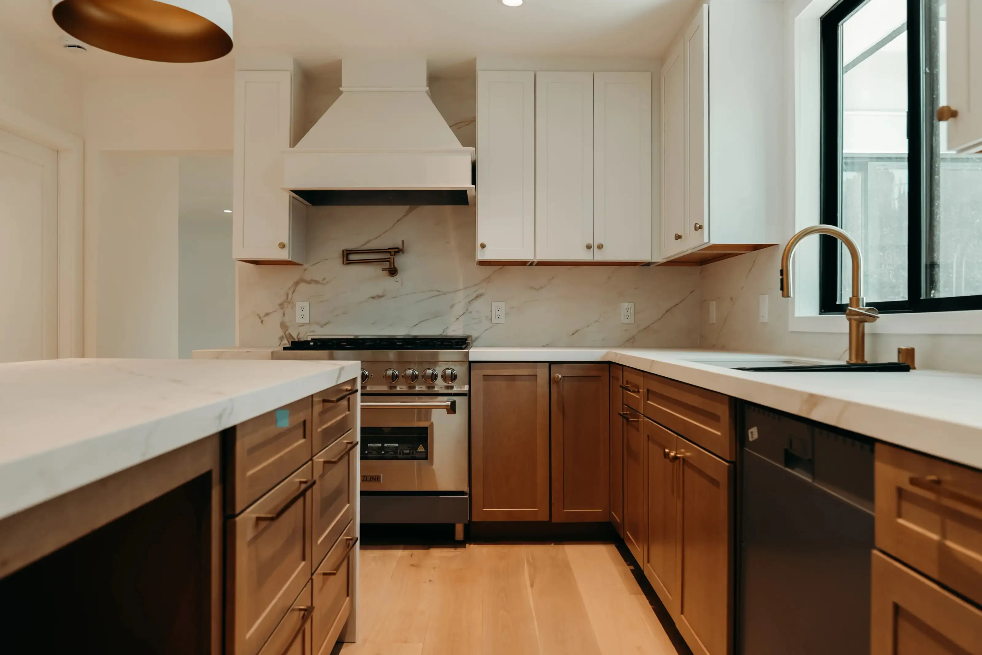 Transitional kitchen remodel in San Jose featuring white upper cabinets, natural wood lower cabinets, marble countertops, and brass fixtures for a warm modern design.