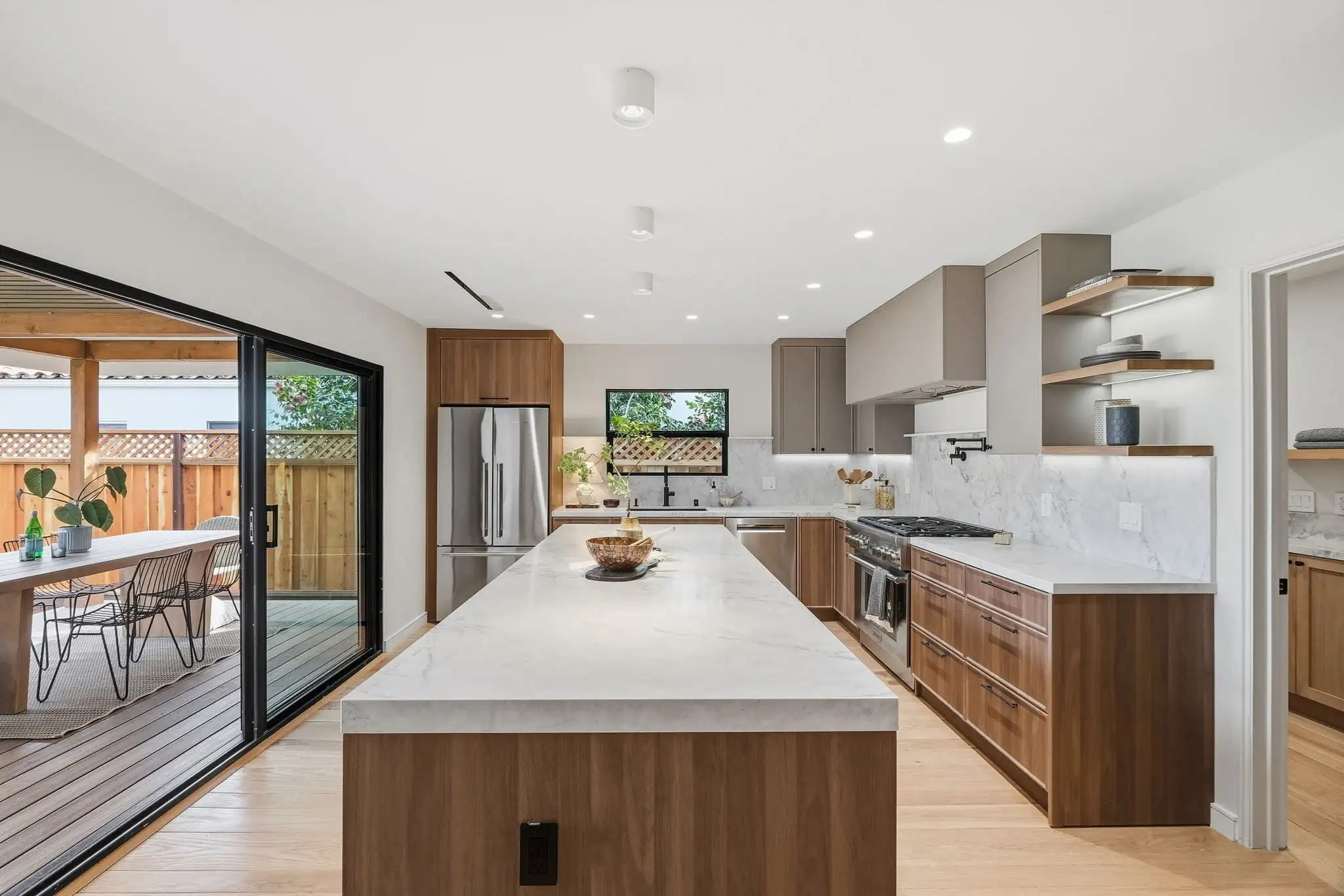 Modern kitchen remodel with walnut cabinets, marble countertops, center island, stainless appliances, and sliding glass